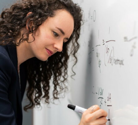 Frau beim Aufschreiben einer Formel auf eine Tafel
