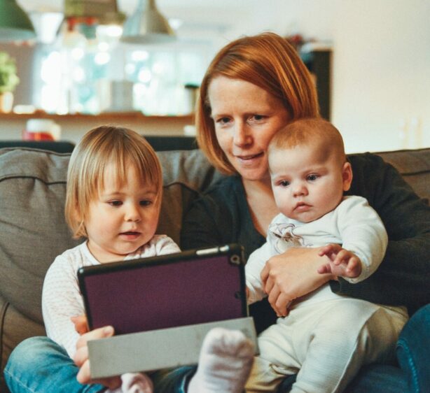 Frau mit zwei Kindern und Tablet auf der Couch