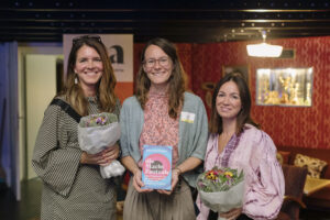 Vera Steinhäuser, Alexandra Wolk und Saskia Veenenbos im Gruppenfoto mit Blumen und dem vorgestellten Buch.