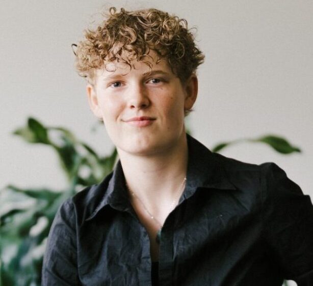 Eine jugendliche Person sitzt auf einem Hocker.